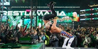 a wrestler doing a handstand in front of a crowd