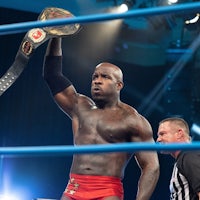 a wrestler is holding up a belt in a wrestling ring